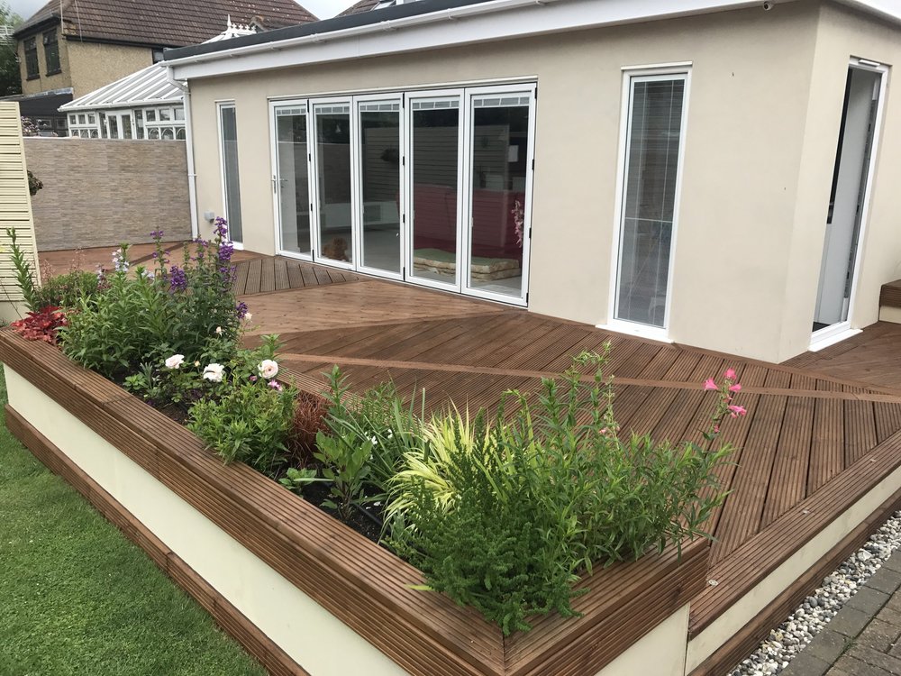 Garden deck with planted borders and sliding doors in Grays, Essex